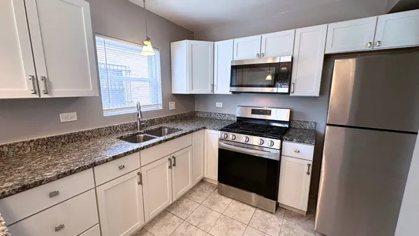 a kitchen with granite countertop white cabinets and refrigerator