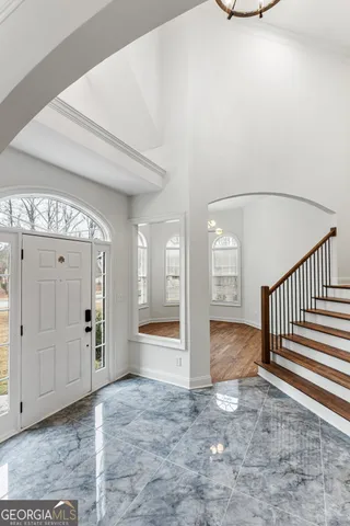a view of an empty room with wooden floor and stairs