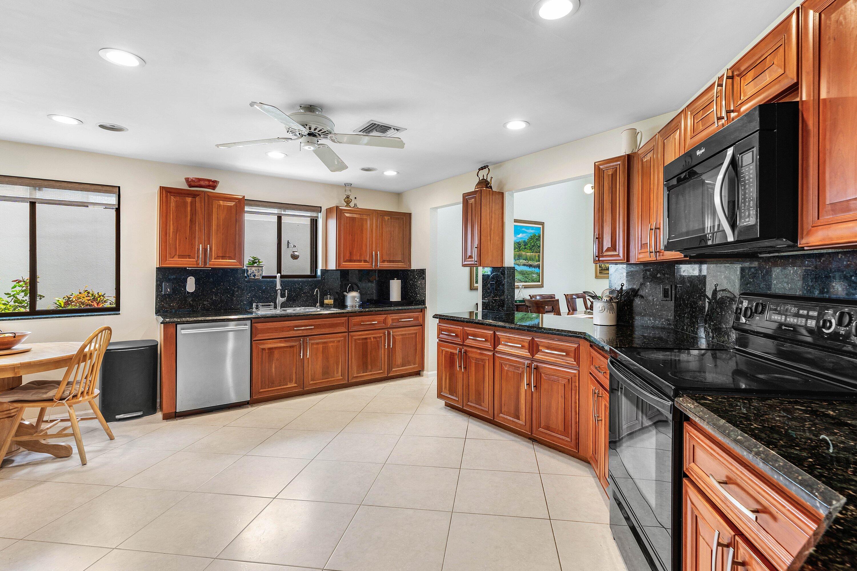 6514 Via Rosa Boca Raton, FL 33433 - Photo 12 of 27 a large kitchen with stainless steel appliances granite countertop a stove top oven a sink dishwasher a dining table and chairs with wooden floor
