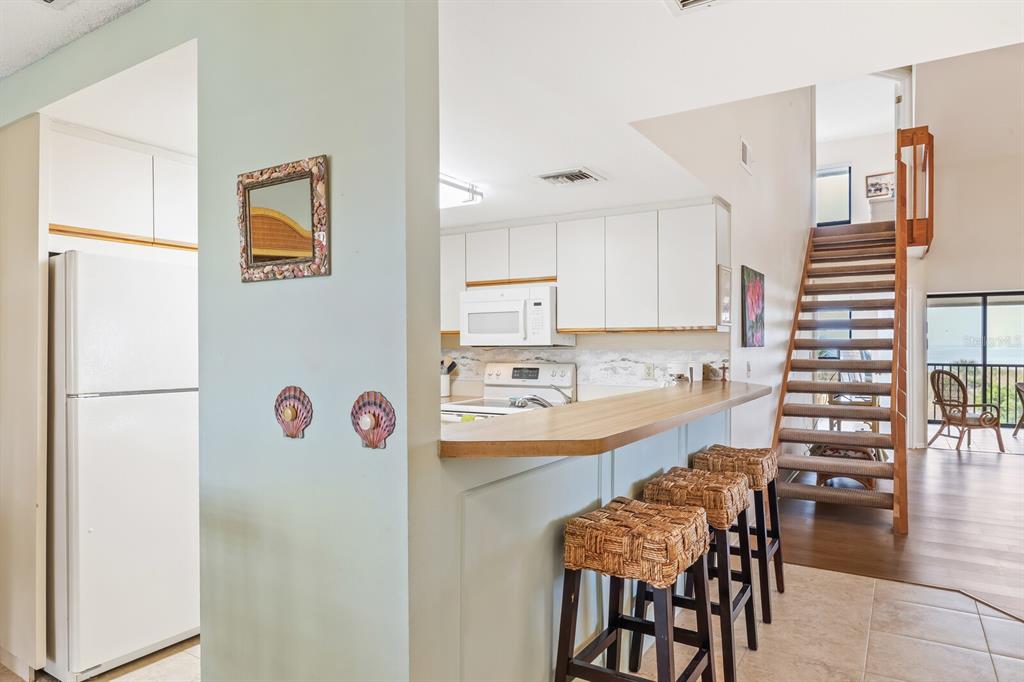 5000 Gasparilla Road, Unit 76B Boca Grande, FL 33921 - Photo 13 of 44 a kitchen with a refrigerator and chairs