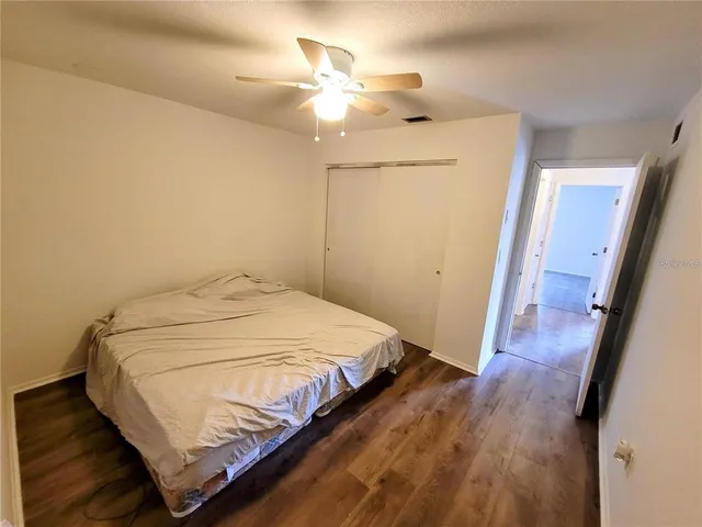 an empty room with wooden floor chandelier and windows