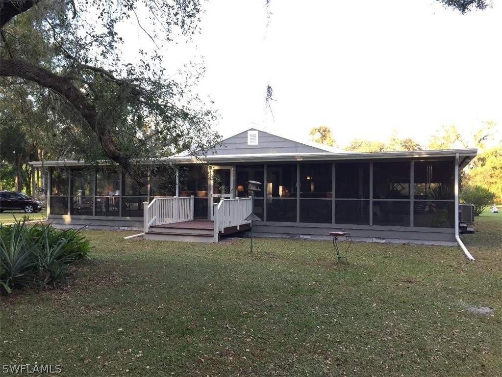 3031 Packinghouse Road Alva, FL 33920 - Photo 3 of 24 a front view of a house with a patio and a garden