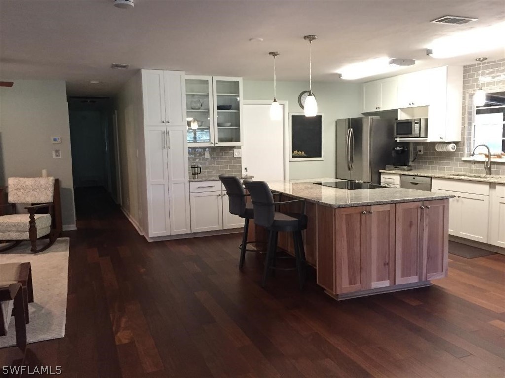 3031 Packinghouse Road Alva, FL 33920 - Photo 7 of 24 a kitchen with stainless steel appliances kitchen island granite countertop wooden floors and white cabinets
