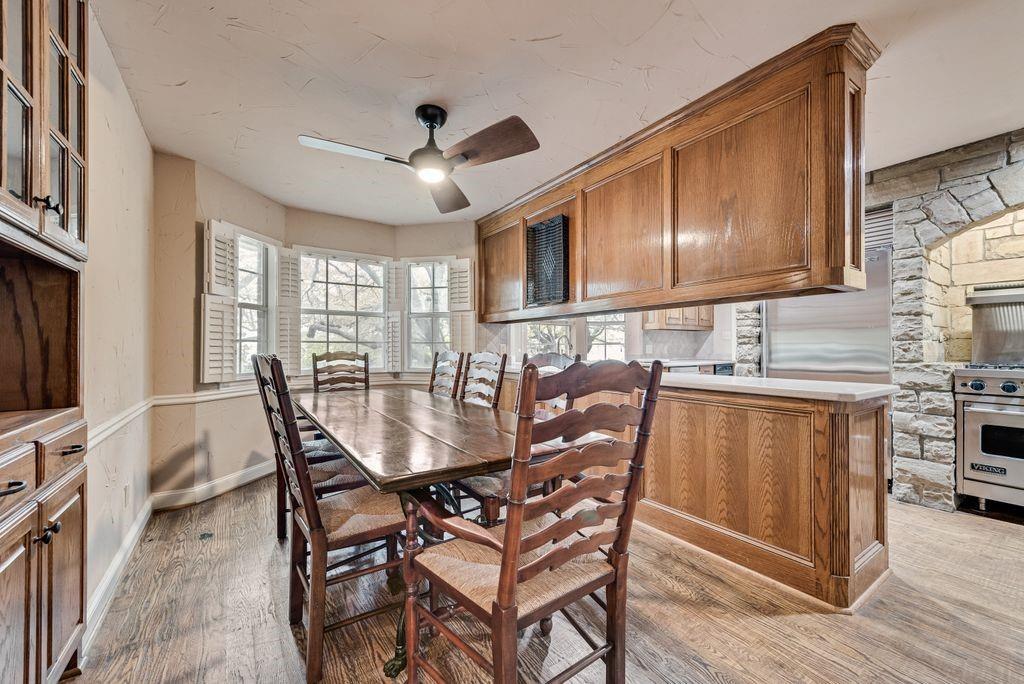 2 Eastshore Road Heath, TX 75032 - Photo 20 of 40 Wood-finish flooring, bay windows with plantation shutters, wood paneling, stone archway, and stainless steel range