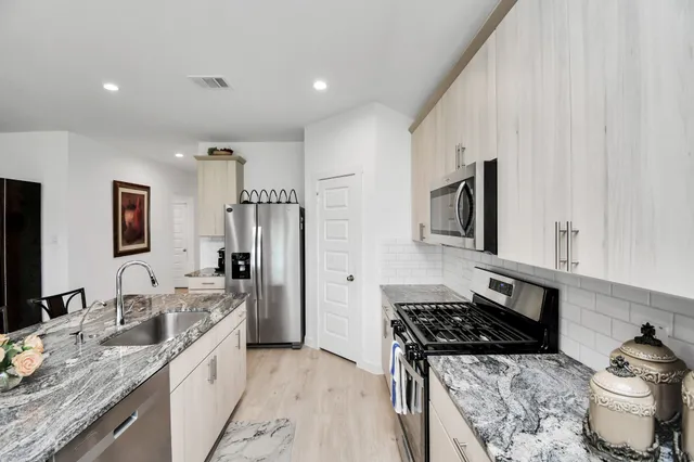 a kitchen with stainless steel appliances granite countertop a sink stove refrigerator and cabinets