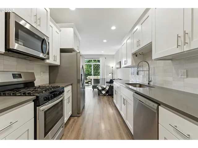 a kitchen with stainless steel appliances a sink dishwasher a stove and a microwave oven with cabinets
