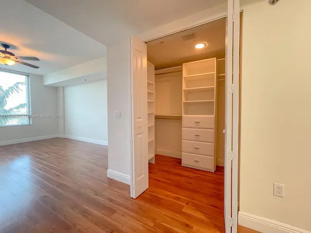 an empty room with wooden floor closet and windows