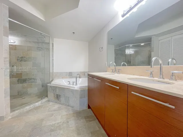 a bathroom with a tub sink mirror and shower