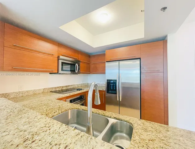 a kitchen with stainless steel appliances granite countertop a sink and a refrigerator