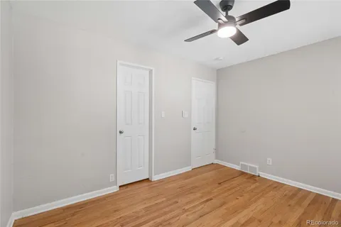 a view of empty room with wooden floor and fan