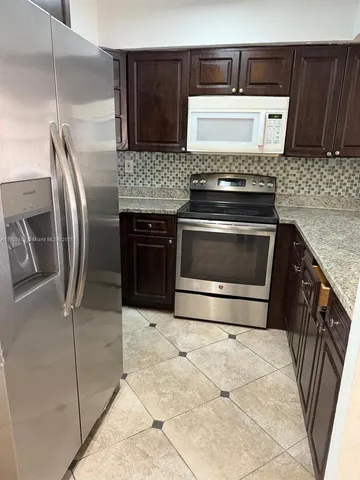 a kitchen with granite countertop a stove and a refrigerator