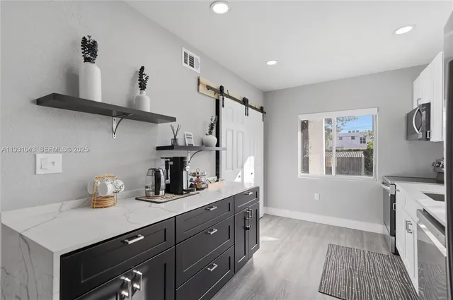 a kitchen with stainless steel appliances a sink a window and cabinets