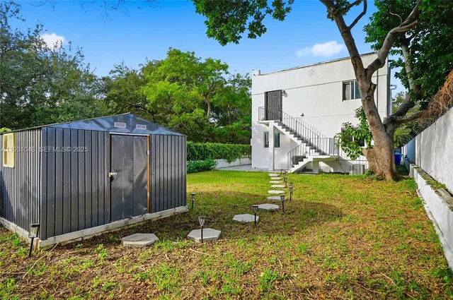 a view of backyard with wooden fence and large trees