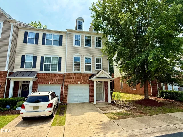 a front view of a building with a garden and trees