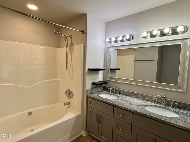 a bathroom with a granite countertop sink mirror and a bathtub