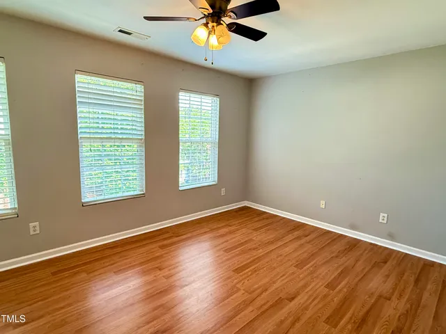 a view of an empty room with window and wooden floor