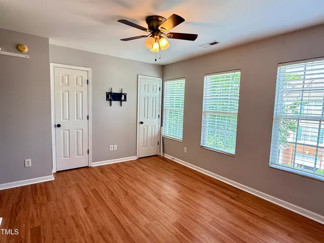 a view of empty room with wooden floor and fan