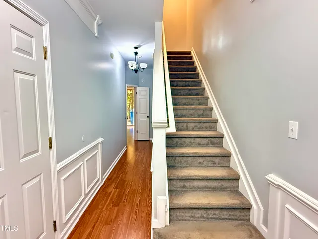 a view of staircase with wooden floor and lots of frames on wall