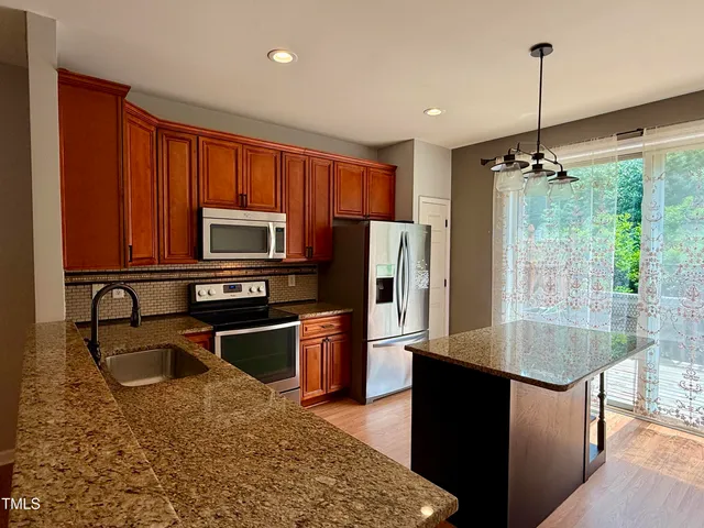 a kitchen with kitchen island a counter top space appliances and a sink
