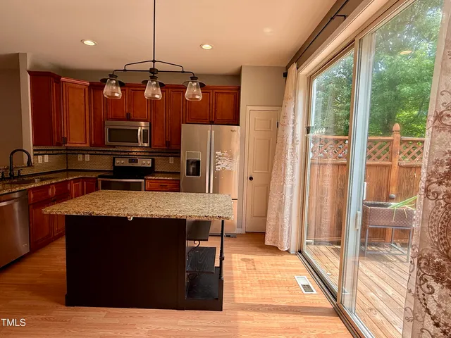 a kitchen with stainless steel appliances granite countertop a stove a refrigerator a sink and dishwasher with wooden floor