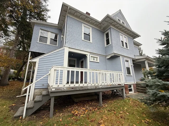 a view of a house with a wooden deck and furniture