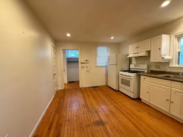 a kitchen with a refrigerator and white cabinets