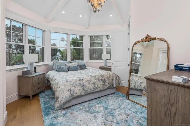 a spacious bedroom with a bed a table and large windows