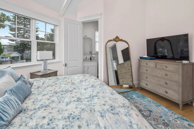 a spacious bedroom with a bed and wooden floor