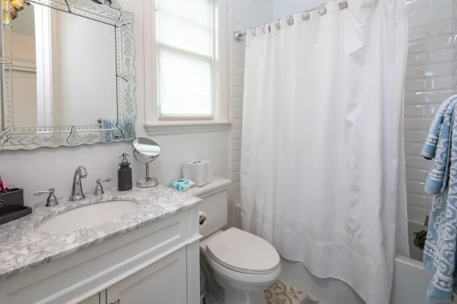 a bathroom with a granite countertop sink toilet and mirror