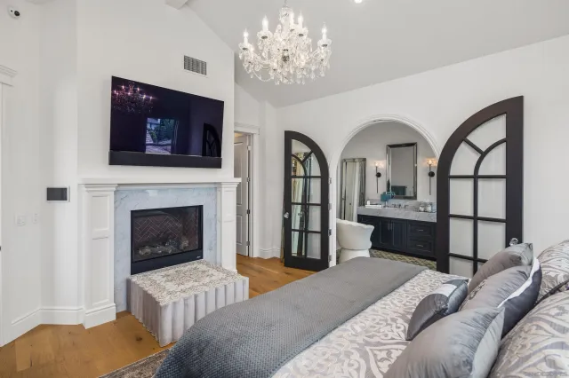 a bedroom with a bed a fireplace and a chandelier