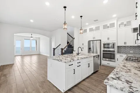 a large kitchen with stainless steel appliances kitchen island granite countertop a stove and a refrigerator
