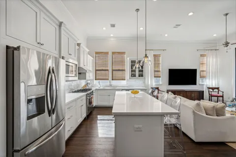 a large kitchen with stainless steel appliances kitchen island granite countertop a refrigerator a sink dishwasher a couches and flat screen tv