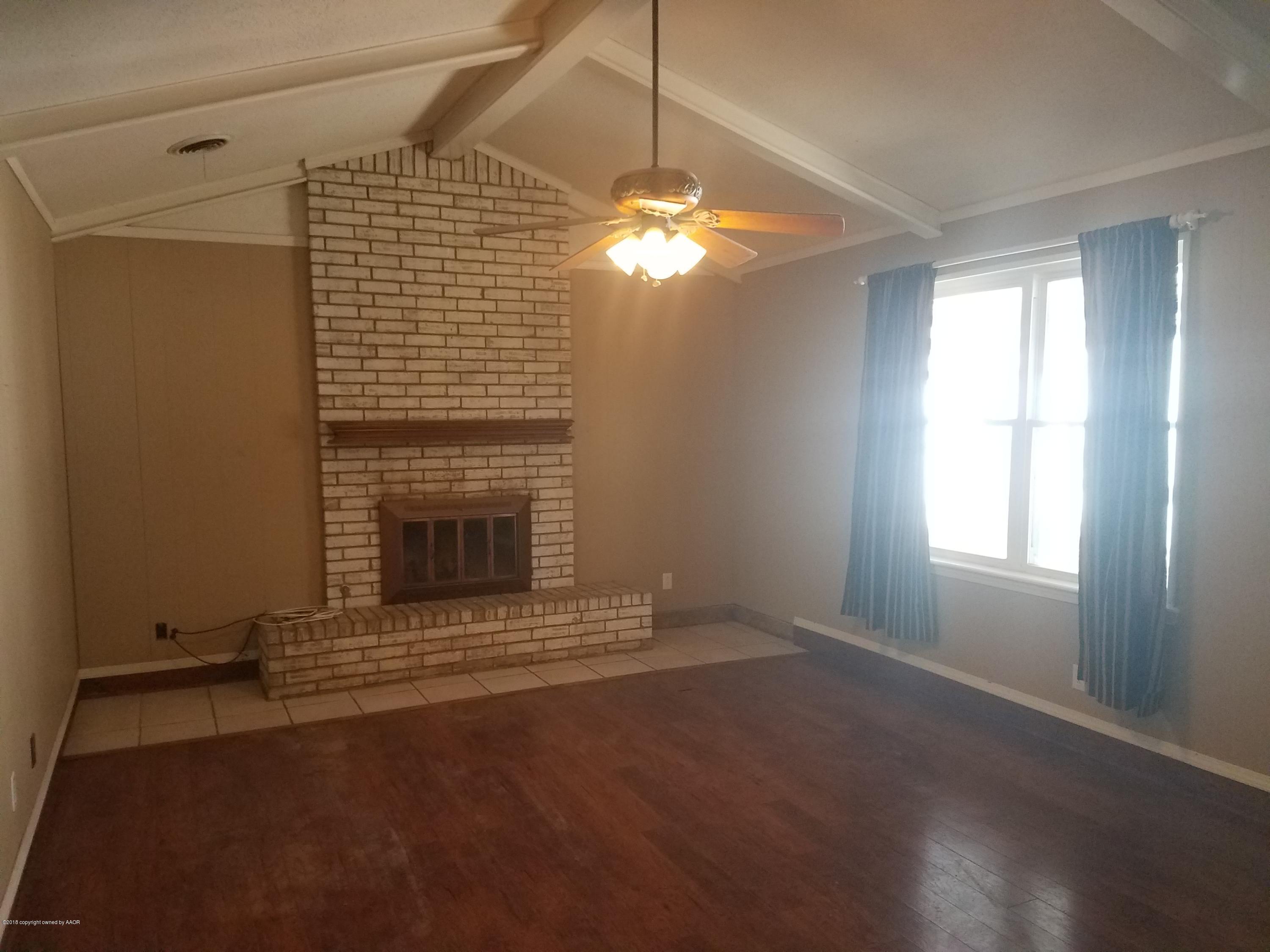 5114 Azalea Avenue Amarillo, TX 79110 - Photo 5 of 13 a view of an empty room with a fireplace and a window