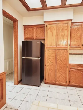 a view of a refrigerator in kitchen and an empty room with wooden floor