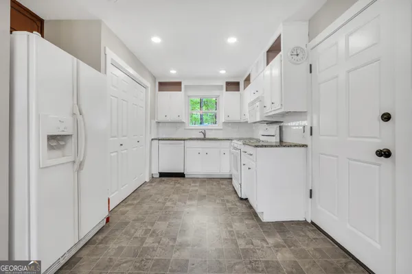 a kitchen with white cabinets and white appliances