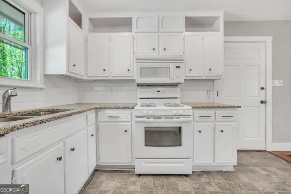 a kitchen with white cabinets and white appliances