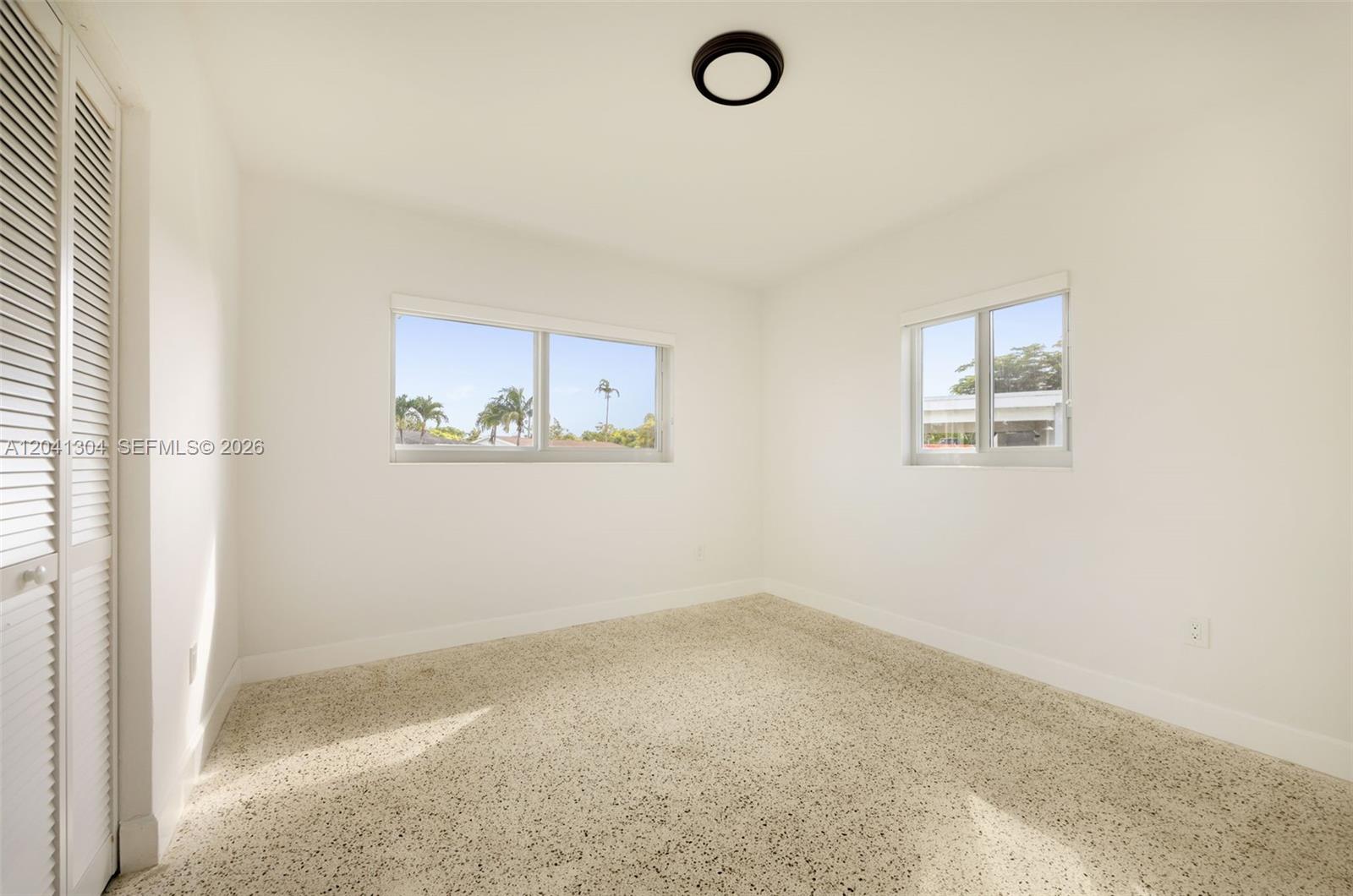 10340 Southwest 157th Street Miami, FL 33157 - Photo 15 of 24 Bedroom – Bright secondary bedroom featuring multiple windows that invite natural light throughout the day. A neutral color palette and closet storage provide a comfortable, move-in-ready space.