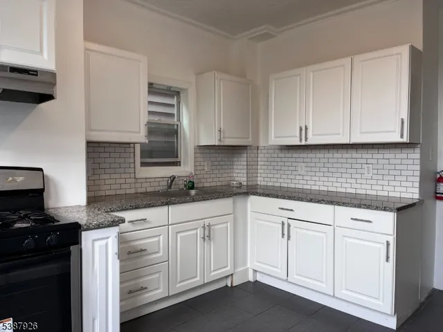 a kitchen with white cabinets and sink