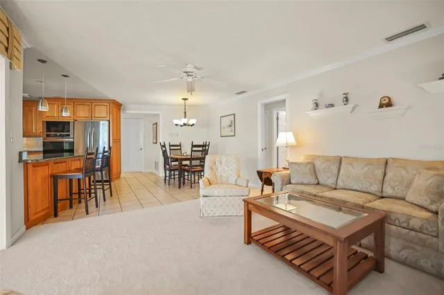 a view of a white house next to a yard with plants and large tree