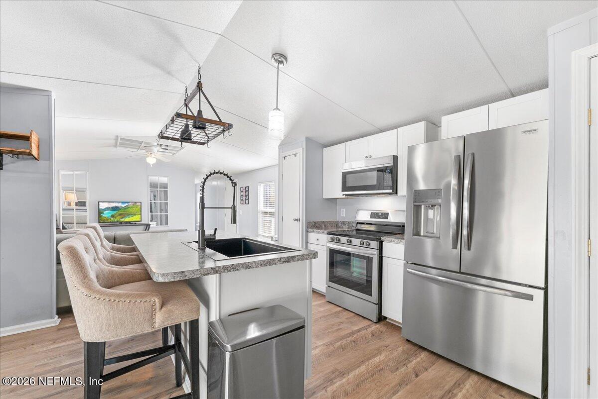 4070 Pinto Road Middleburg, FL 32068 - Photo 18 of 37 a kitchen with stainless steel appliances granite countertop a sink a stove a refrigerator a microwave a dining table and chairs with wooden floor