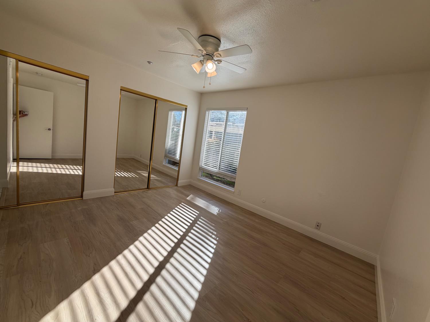 6241 Riverside Boulevard, Unit 112 Sacramento, CA 95831 - Photo 11 of 33 a view of an empty room with wooden floor and a ceiling fan