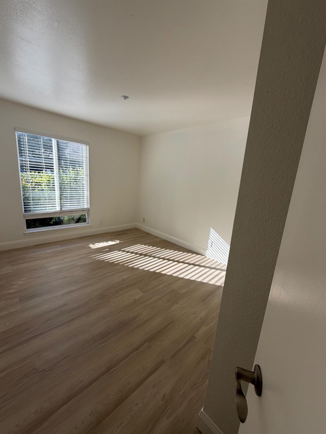 6241 Riverside Boulevard, Unit 112 Sacramento, CA 95831 - Photo 19 of 33 an empty room with wooden floor and windows
