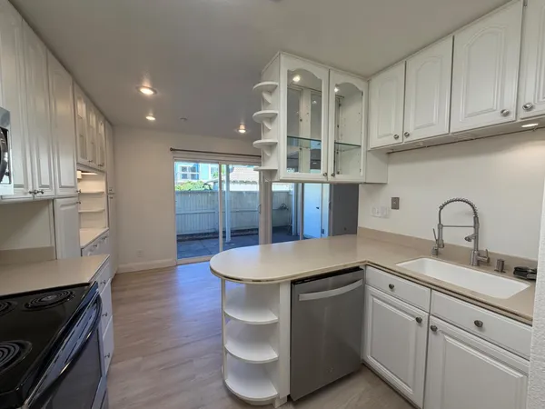 a kitchen with stainless steel appliances granite countertop a sink a stove and wooden floors