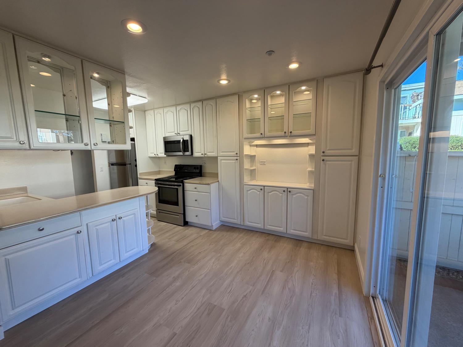 6241 Riverside Boulevard, Unit 112 Sacramento, CA 95831 - Photo 5 of 33 a kitchen with kitchen island granite countertop wooden floors and white stainless steel appliances