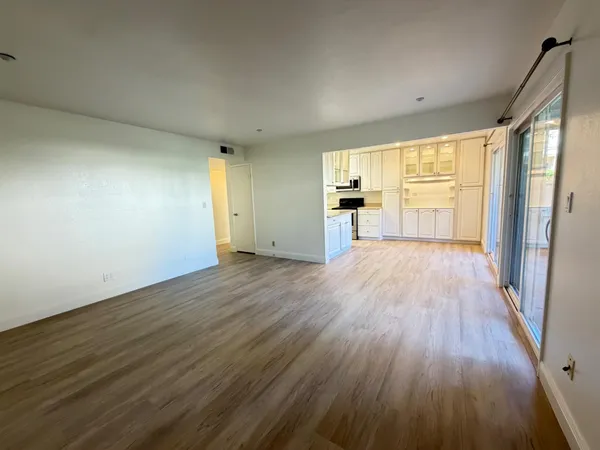 a view of a big room with wooden floor and windows