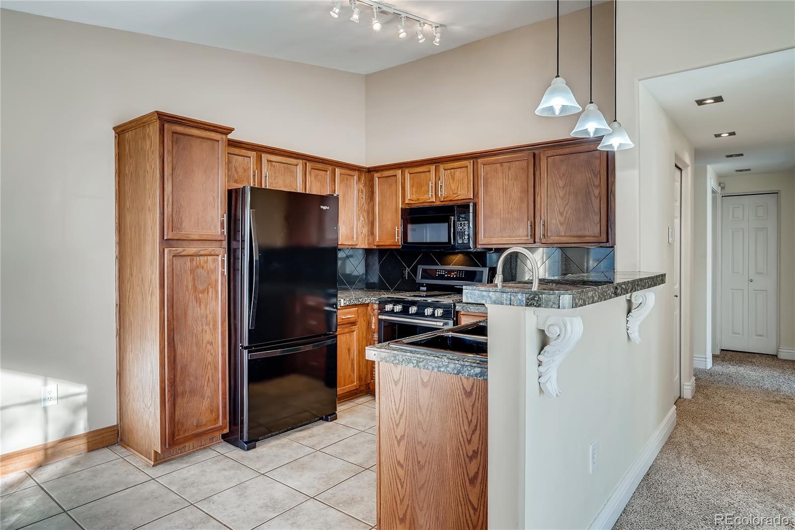 8459 South Little Rock Way, Unit 201 Highlands Ranch, CO 80126 - Photo 8 of 28 a kitchen with a refrigerator a sink and a stove