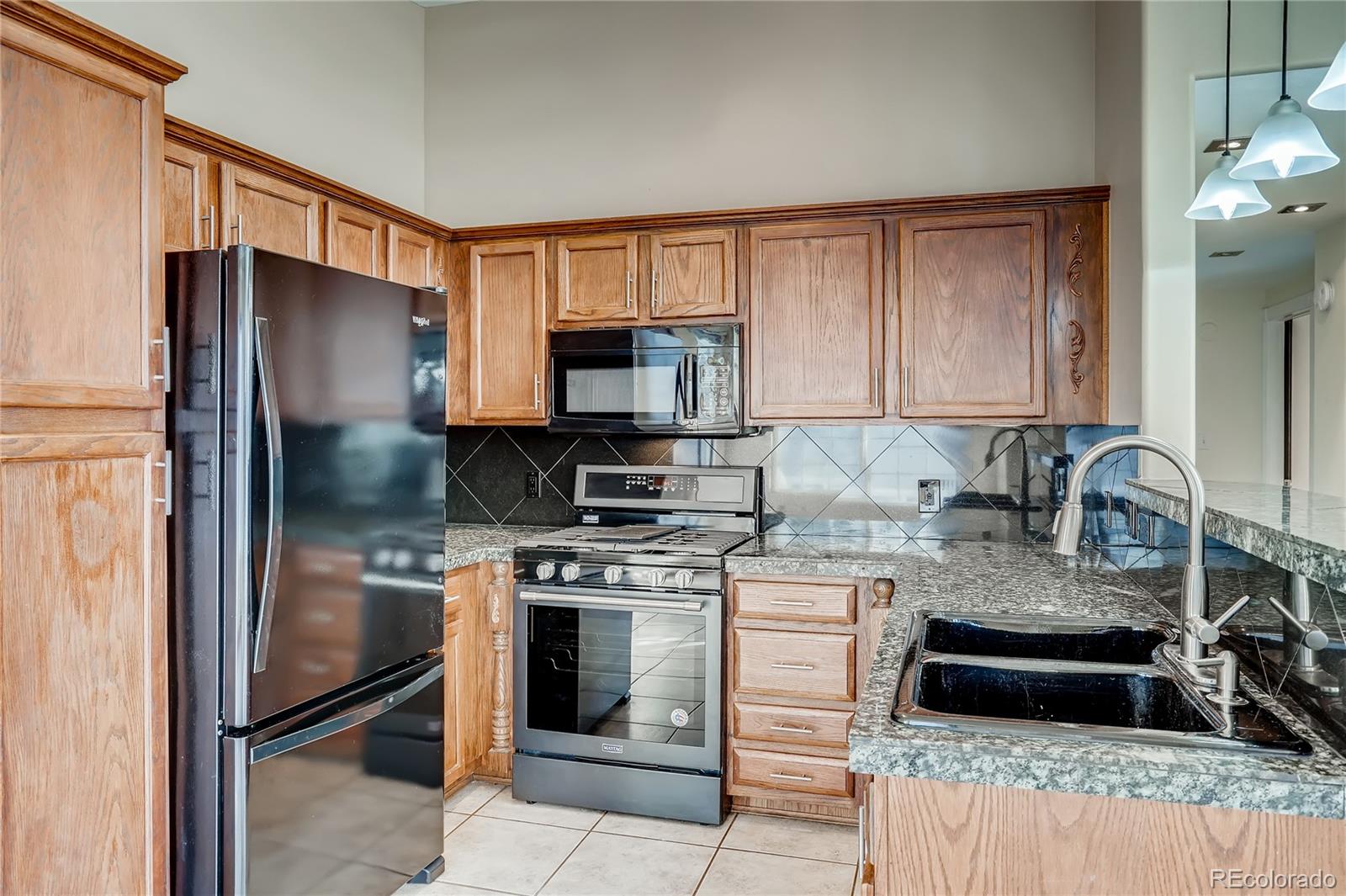8459 South Little Rock Way, Unit 201 Highlands Ranch, CO 80126 - Photo 9 of 28 a kitchen with stainless steel appliances granite countertop a stove a refrigerator and a sink