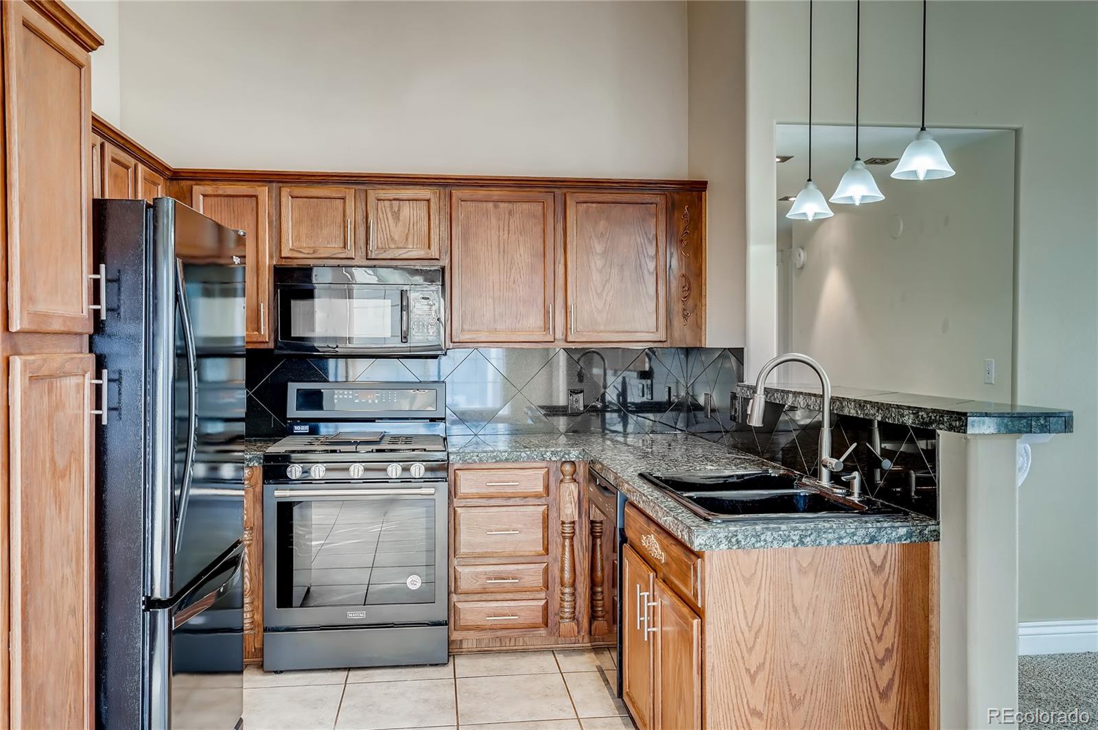 8459 South Little Rock Way, Unit 201 Highlands Ranch, CO 80126 - Photo 10 of 28 a kitchen with stainless steel appliances granite countertop a stove a sink and a refrigerator