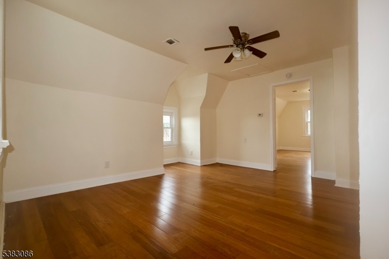 34 Hedden Terrace, Unit 3 Newark, NJ 07108 - Photo 3 of 13 an empty room with wooden floor and a ceiling fan