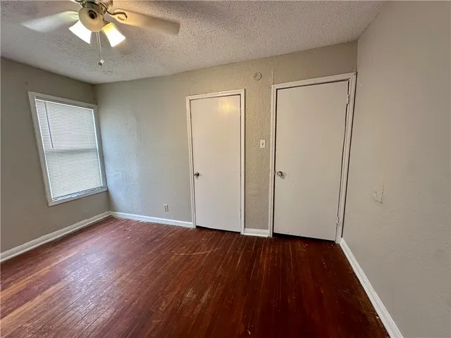 an empty room with wooden floor chandelier fan and windows
